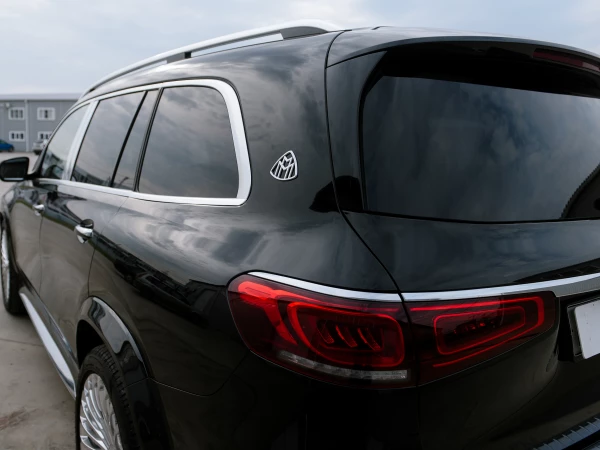MERCEDES-MAYBACH GLS 600 - вид сзади на левую часть кузова, эмблема “Maybach”,  задний фонарь