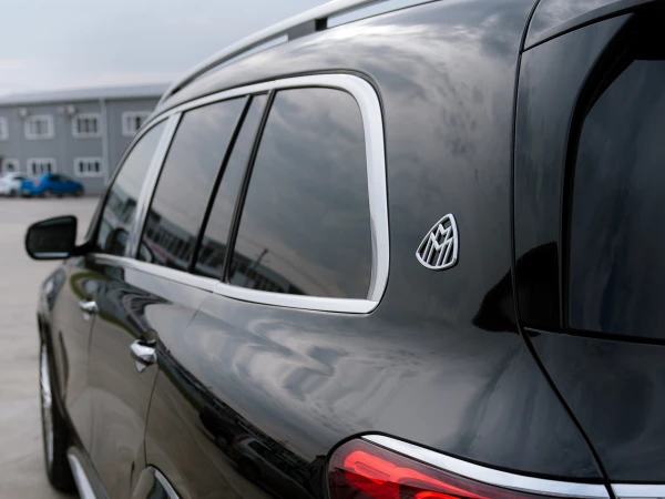 MERCEDES-MAYBACH GLS 600 - вид сзади на левую часть кузова, эмблема “Maybach”,  задний фонарь